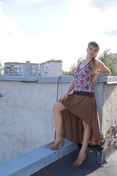 Menina sexy na moda bonita em saltos altos se divertindo em um skate no telhado. o contexto de uma fábrica abandonada . — Fotografia de Stock