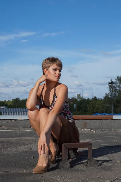 Модная сексуальная девушка на высоких каблуках развлекается на скейтборде на крыше. фон заброшенной фабрики . — стоковое фото