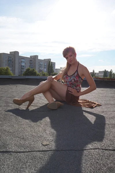 Beautiful fashionable sexy girl in high heels having fun on a skateboard  the roof.  the background of an abandoned factory. — Stock Photo, Image