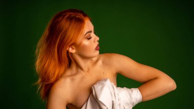 Stüdyoda yeşil arka planda beyaz gömlekli çıplak kızıl kadın. 