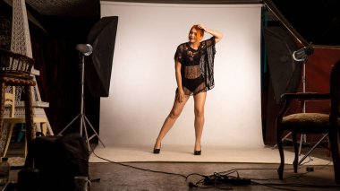 Stüdyoda açık arkaplanda poz veren koyu renk elbiseli güzel kızıl saçlı kadın. 