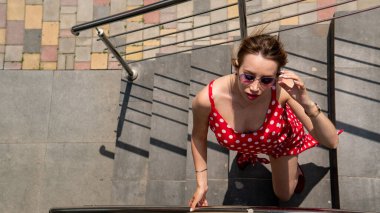 Şehir caddesinde poz veren yaz kırmızı elbiseli çekici genç bir kadın. 