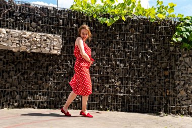 Yazın giydiği kırmızı elbiseli çekici genç kadın dışarıda poz veriyor 