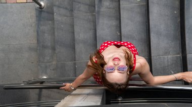 Şehir caddesinde poz veren yaz kırmızı elbiseli çekici genç bir kadın. 