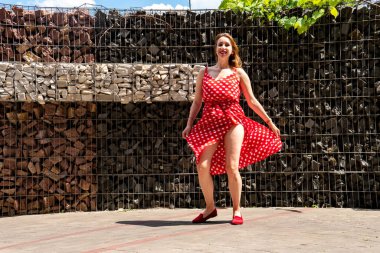 Yazın giydiği kırmızı elbiseli çekici genç kadın dışarıda poz veriyor 