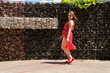 Yazın giydiği kırmızı elbiseli çekici genç kadın dışarıda poz veriyor 