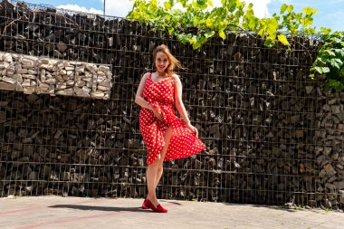 Yazın giydiği kırmızı elbiseli çekici genç kadın dışarıda poz veriyor 