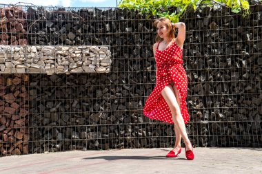 Yazın giydiği kırmızı elbiseli çekici genç kadın dışarıda poz veriyor 