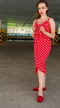 Park yerinde poz veren yaz kırmızısı elbiseli çekici genç bir kadın.