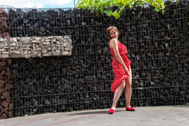 Yazın giydiği kırmızı elbiseli çekici genç kadın dışarıda poz veriyor 