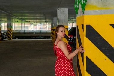 Park yerinde poz veren yaz kırmızısı elbiseli çekici genç bir kadın.