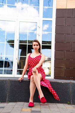 Yazın giydiği kırmızı elbiseli çekici genç kadın dışarıda poz veriyor 