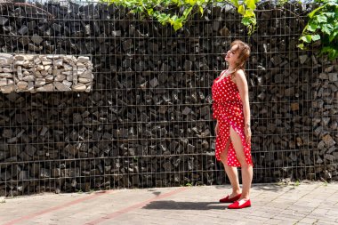 Yazın giydiği kırmızı elbiseli çekici genç kadın dışarıda poz veriyor 