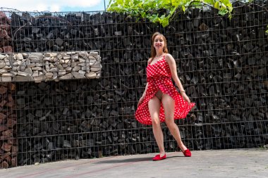 Yazın giydiği kırmızı elbiseli çekici genç kadın dışarıda poz veriyor 