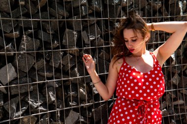 Yazın giydiği kırmızı elbiseli çekici genç kadın dışarıda poz veriyor 