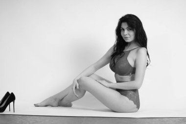 Stüdyoda beyaz arka planda poz veren seksi esmer kadın. 