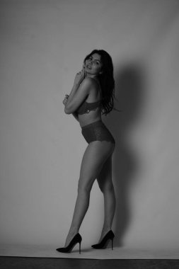 Stüdyoda beyaz arka planda poz veren seksi esmer kadın. 