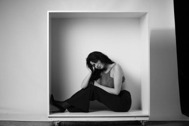 Stüdyoda beyaz arka planda dekoratif bir kutuda poz veren iç çamaşırlı, güzel esmer kadın. 