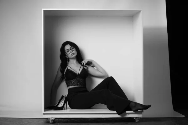 セクシーな美しいブルネット女性でランジェリーとトレンディーなベルボトムスパンツPosingで装飾箱でスタジオ上の白の背景 — ストック写真