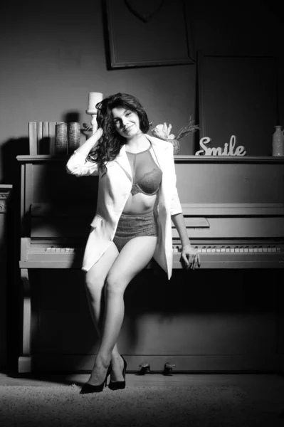 穿着内衣和白色夹克的漂亮的黑发女人在录音棚里弹钢琴 — 图库照片