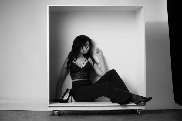 セクシーな美しいブルネット女性でランジェリーとトレンディーなベルボトムスパンツPosingで装飾箱でスタジオ上の白の背景 — ストック写真