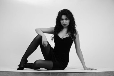 Güzel esmer kadın, gece elbisesi ve beyaz atölyede naylon tayt giymiş. 