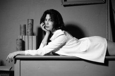 Beyaz ceketli güzel esmer kadın stüdyoda piyanoyla poz veriyor. 