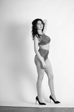 Beyaz stüdyo arka planında iç çamaşırı giyen güzel esmer kadın.