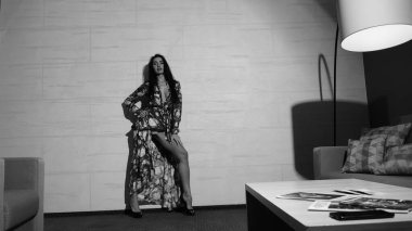 Odada poz veren güzel genç bir kadın, siyah beyaz bir fotoğraf.