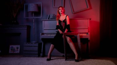 Gece elbisesi içinde piyanoyla poz veren güzel ve çekici bir kadın.