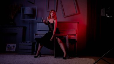 Gece elbisesi içinde piyanoyla poz veren güzel ve çekici bir kadın.
