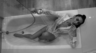 Banyoda poz veren erkek gömlekli güzel bir kadın, siyah beyaz bir fotoğraf.