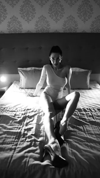 部屋のベッドの上でポーズをとっている美しい若い女性黒と白 — ストック写真