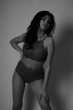 Beyaz stüdyo arka planında iç çamaşırı giyen güzel esmer kadın.