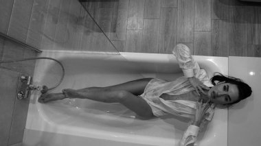 Banyoda poz veren erkek gömlekli güzel bir kadın, siyah beyaz bir fotoğraf.