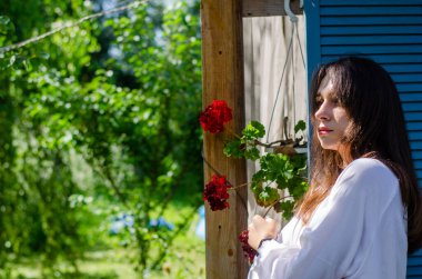 Güneşli bir günde evin yakınındaki yaz bahçesinde poz veren güzel bir genç kız.