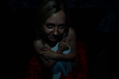 Üstsüz sarışın, siyah arka planda beyaz bir bez ile kaplı.