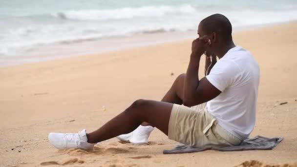 Afro Amerikaanse Sportieve Man Zit Het Strand Kijkt Naar Zee Stockvideo's