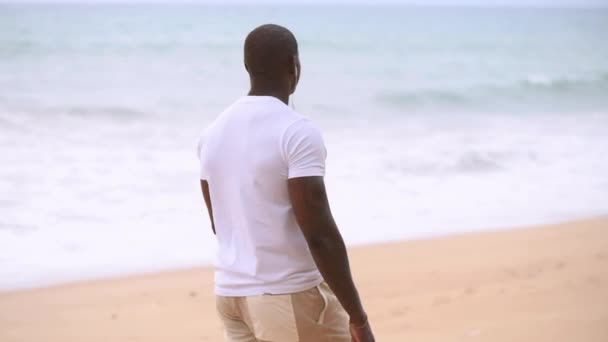 Afro Amerikaanse sportieve man loopt langs het strand en kijkt naar de zee en het luisteren naar muziek Rechtenvrije Stockvideo's