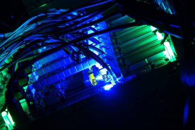 Vibrant light illuminates cables and technology in a dark environment, showcasing the intricate beauty of electronic connections and server systems in operation.