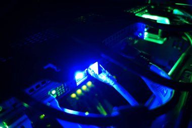 Close-up view of glowing blue lights illuminating networking equipment and cables, showcasing the intricate connections in a data center environment.