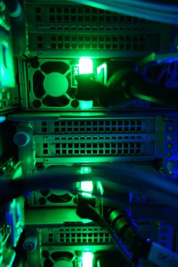 Close-up view of illuminated server equipment showcasing green lights and cables, symbolizing advanced technology and modern data storage in a high-tech environment.
