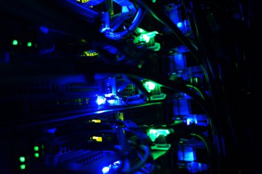 Close-up view of network cables and illuminated lights within a server rack, showcasing the intricate technology of modern data infrastructure.