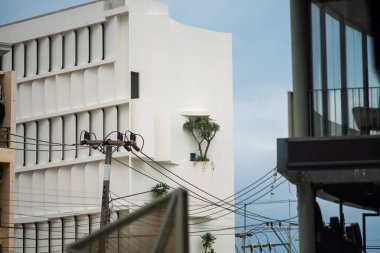 Bulutlu bir gökyüzüne karşı kurulmuş, çarpıcı yeşillik içeren modern bir bina tasarımı. Bu görüntü kentsel mimari ve doğa arasındaki dengeyi yakalar..