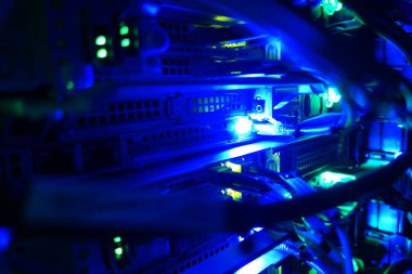 Mavi ışıkla aydınlatılan sunucu odası kablolarının yakın görüntüsü, veri yönetimi ve iletişim sistemleri için hayati önem taşıyan modern bir teknoloji ortamı sergiliyor.