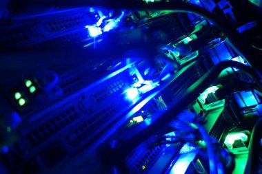 Aydınlatılmış sunucu raflarının, karmaşık kablolar arasında canlı mavi ışıkları gösteren, bir veri merkezinde modern teknoloji ve dijital altyapıyı gösteren yakın çekim görüntüsü.