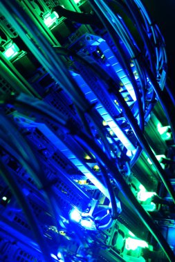 Modern teknoloji kurulumunda sunucu kablolarını aydınlatan büyüleyici bir mavi ışık görüntüsü veri transferinde yer alan karmaşık bağlantıları ve donanımı vurguluyor.