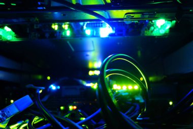 Bir sunucu rafındaki parlayan kabloların ve ışıkların yakın görüntüsü, modern ağ ve bilgisayar ekipmanlarının arkasındaki canlı teknolojiyi sergiliyor.