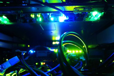 Aydınlatılmış fiber optik kablolar ve parlayan ışıklarla dolu bir sunucu odasının görsel temsili modern teknoloji ve veri ağlarının karmaşıklığını gözler önüne seriyor..