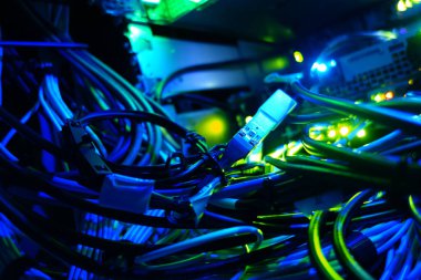 Bu resim, modern teknoloji ve iletişim sistemlerinin karmaşıklığını ve güzelliğini gösteren mavi ışıkta parlayan karmaşık ağ kablolarının ayrıntılı bir görüntüsünü sergiliyor..